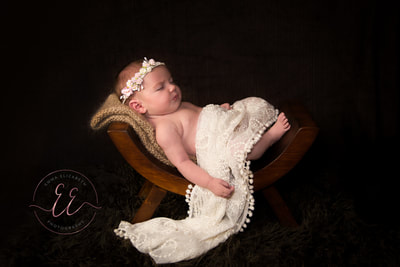 Newborn portraiture. Baby laying on a wooden curved stool prop. Newborn photography Emma Elizabeth Photography studio in St Neots, Huntingdon, Cambridgeshire