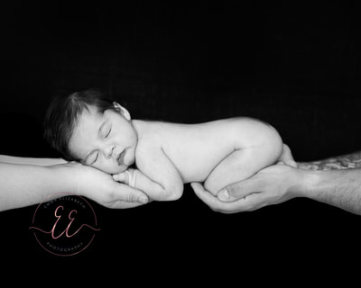 Black and white photo, newborn baby held in parents hands. Newborn photography in St Neots, Huntingdon, Cambridgeshire